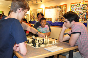 GM Mesgen Amanov reviews Tommy Ulrich's name with Steven Tennant while David Peng and his dad look on.